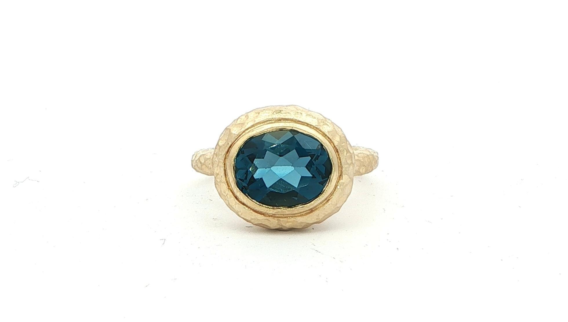 Estate Piece: Solitaire Sideways Bezel-set Oval Blue Topaz Ring with Satin Hammered Finish in Yellow Gold